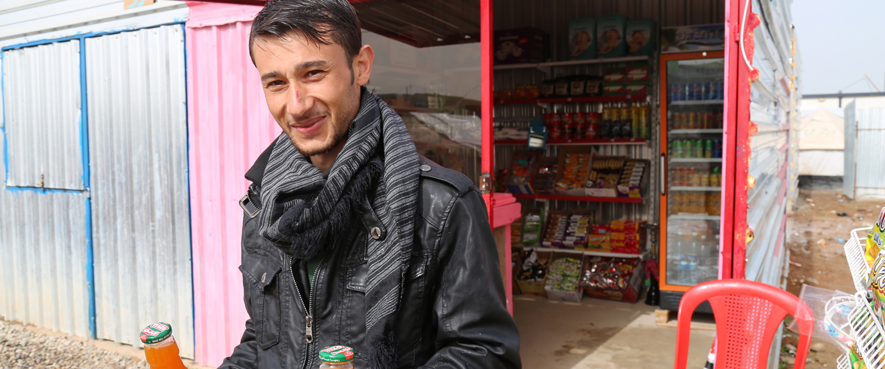 Een Syrische vluchteling voor zijn winkel in het Gawer Gosik-kamp. Mogelijk gemaakt door een gezamenlijk project van de Internationale Organisatie voor Migratie (IOM) en de UNHCR, de organisatie voor vluchtelingen van de Verenigde Naties. | Foto: Taryn Fivek | IOM 2015