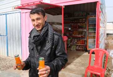 Syrische vluchteling voor zijn winkel in het Gawer Gosik-kamp, Turkije. | Foto: Taryn Fivek | IOM 2015