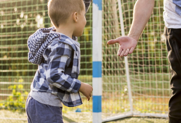 Kind geeft vader high five op voetbalveldje